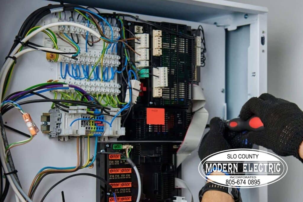 Electrician wiring a control panel with tools.
