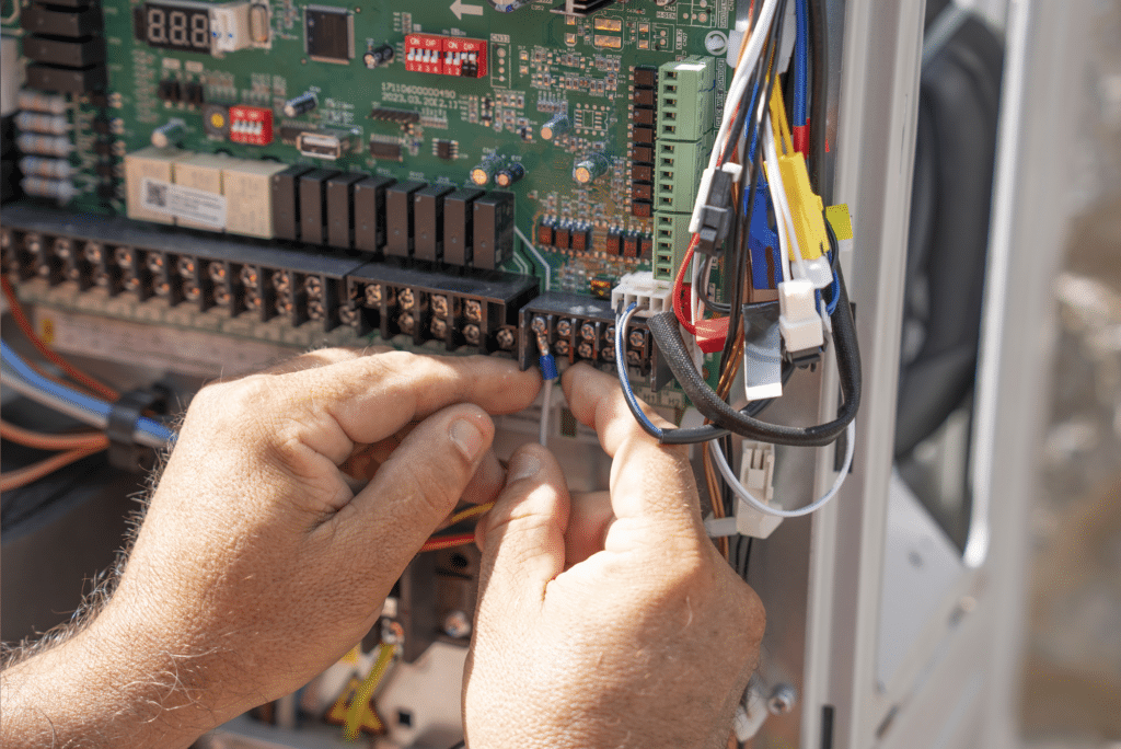 Hands working on electrical circuit board.