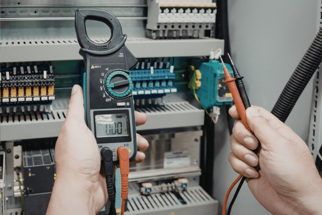 Electrician using multimeter on control panel