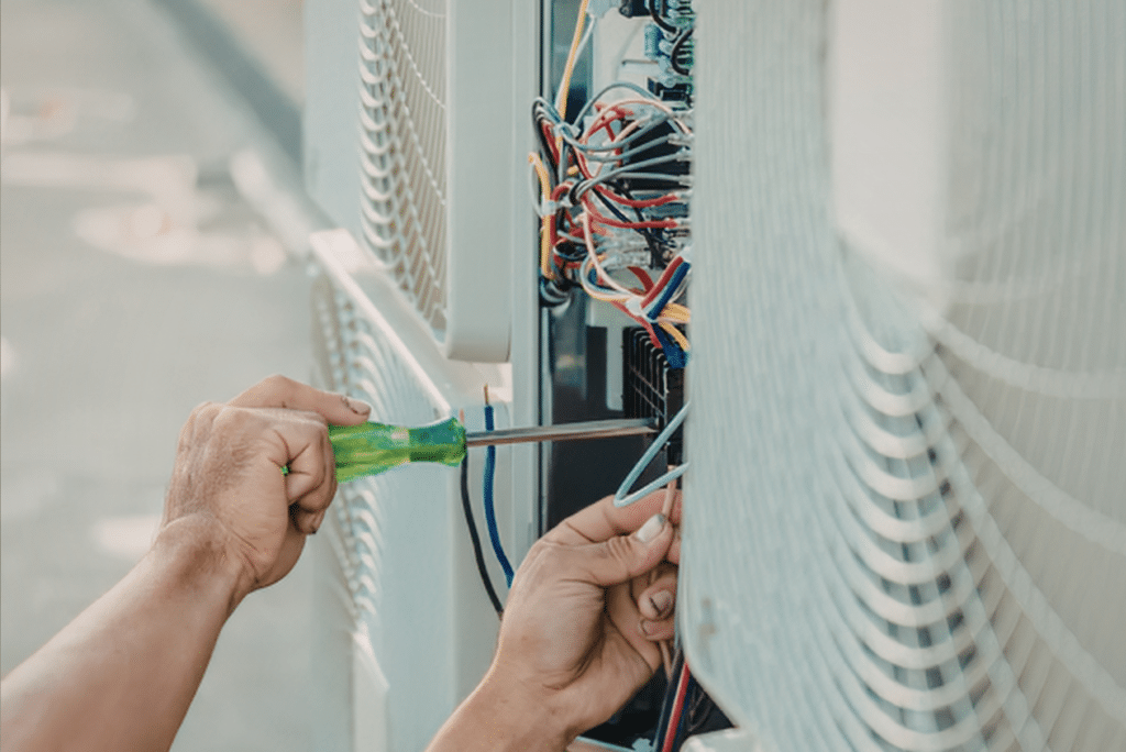 Technician repairing air conditioning unit wiring